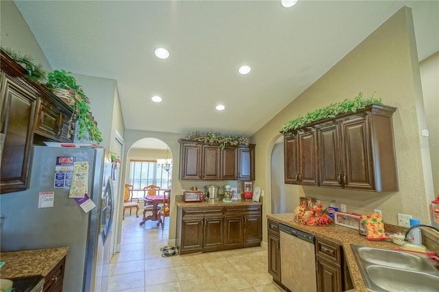 kitchen featuring sink, light stone counters, vaulted ceiling, light tile patterned floors, and appliances with stainless steel finishes