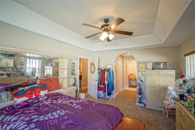 carpeted bedroom featuring a raised ceiling and ceiling fan