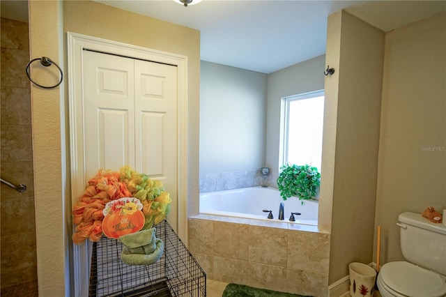 bathroom with tiled tub and toilet