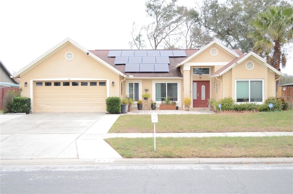 view of front of home with a garage, a front yard, and solar panels