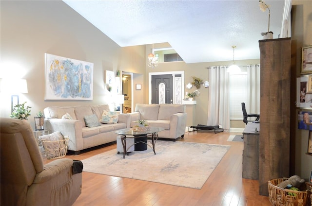 living room with a high ceiling, a textured ceiling, and light wood-type flooring