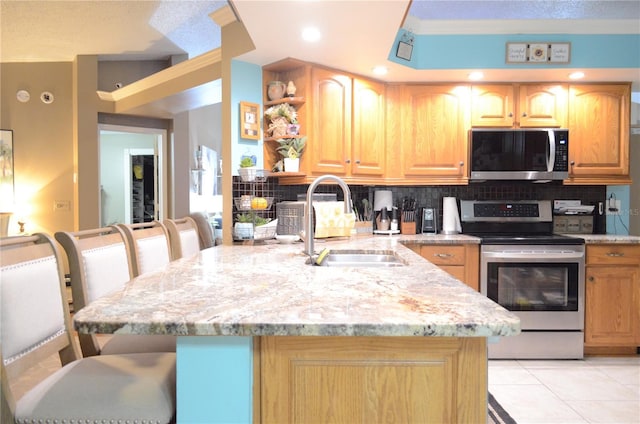 kitchen with light tile patterned flooring, sink, decorative backsplash, stainless steel appliances, and light stone countertops