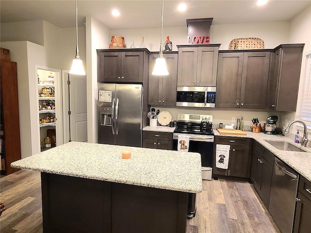 kitchen with sink, appliances with stainless steel finishes, a center island, dark brown cabinetry, and decorative light fixtures