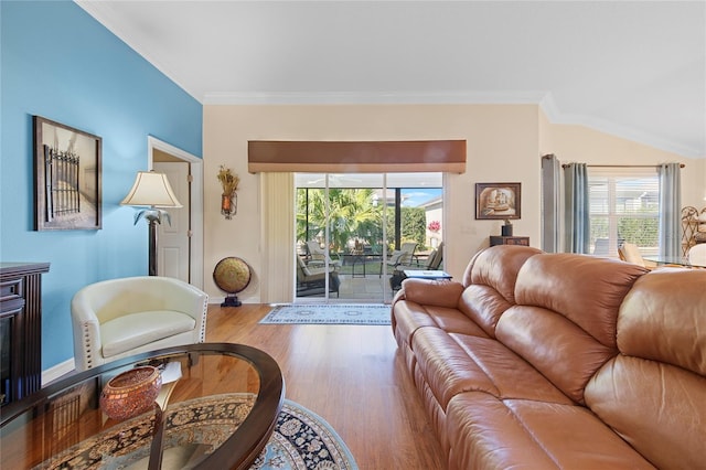 living room with hardwood / wood-style flooring, ornamental molding, and vaulted ceiling