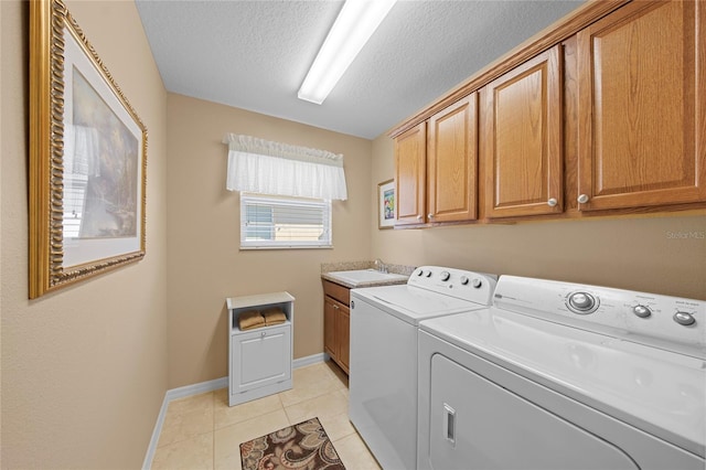 laundry area with sink, cabinets, a textured ceiling, washing machine and clothes dryer, and light tile patterned flooring