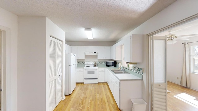 kitchen with a textured ceiling, white cabinets, white appliances, and light hardwood / wood-style flooring