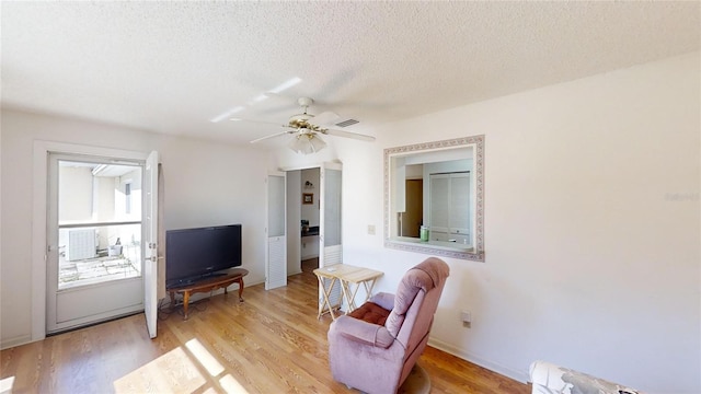 sitting room with ceiling fan, a textured ceiling, and light hardwood / wood-style floors