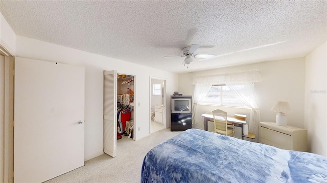 bedroom with ceiling fan, connected bathroom, a textured ceiling, light colored carpet, and a closet