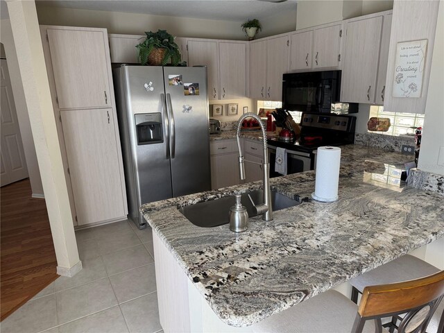 kitchen featuring light stone counters, light tile patterned floors, kitchen peninsula, and appliances with stainless steel finishes