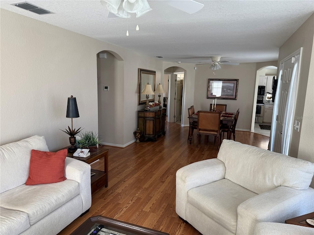 living room with ceiling fan, dark hardwood / wood-style floors, and a textured ceiling