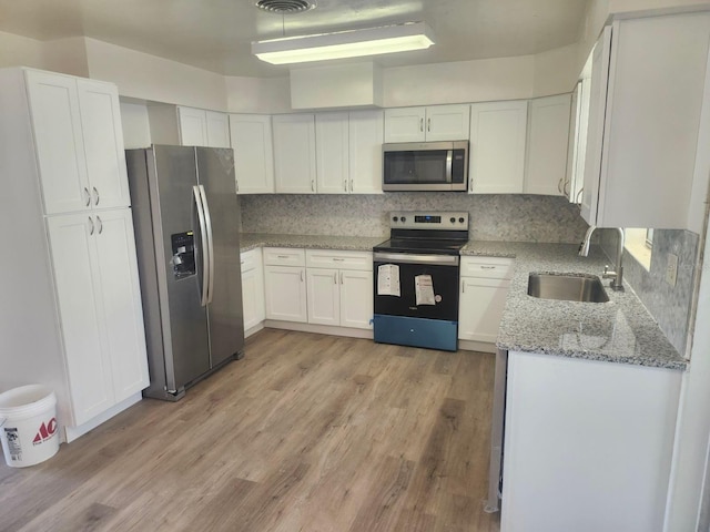 kitchen with sink, white cabinetry, stainless steel appliances, light stone counters, and decorative backsplash