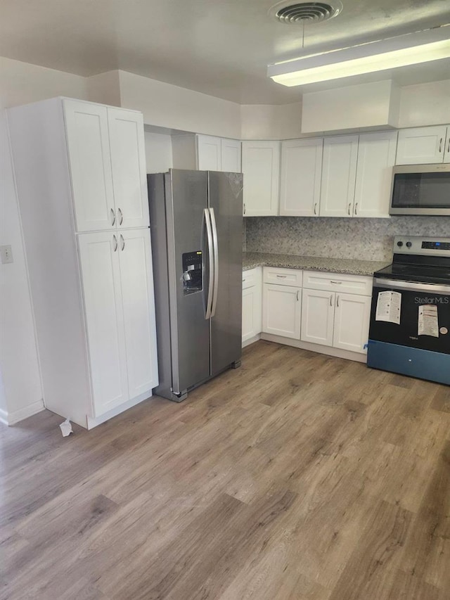 kitchen with white cabinetry, stainless steel appliances, light wood-type flooring, and backsplash