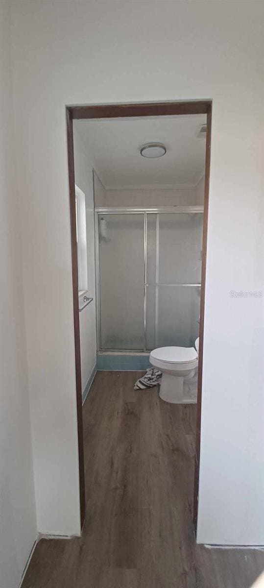 bathroom featuring an enclosed shower, hardwood / wood-style floors, and toilet