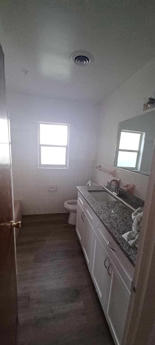 bathroom with vanity, wood-type flooring, tile walls, and toilet