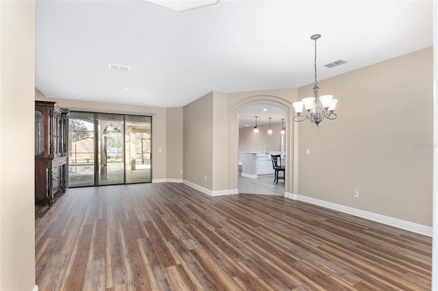 unfurnished room with an inviting chandelier and dark hardwood / wood-style flooring