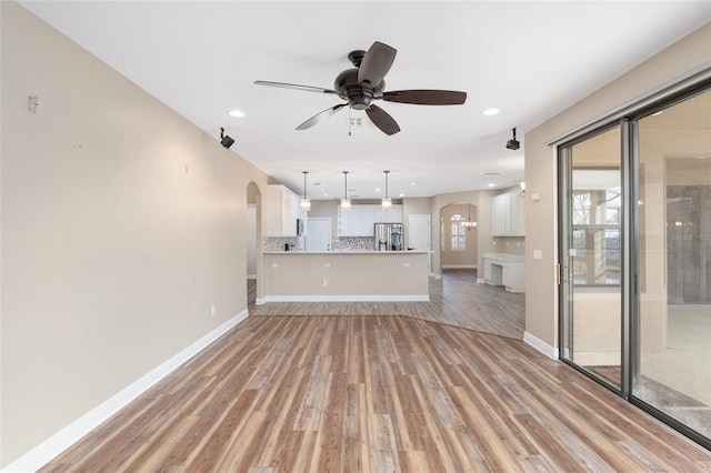 unfurnished living room featuring ceiling fan and light wood-type flooring