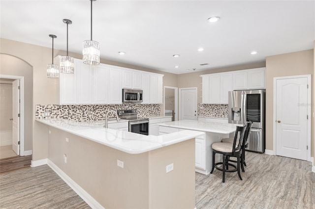 kitchen featuring pendant lighting, white cabinetry, a kitchen breakfast bar, stainless steel appliances, and kitchen peninsula