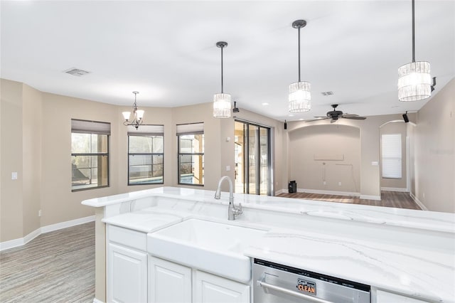 kitchen featuring pendant lighting, sink, light stone countertops, white cabinets, and stainless steel dishwasher