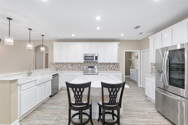 kitchen with appliances with stainless steel finishes, sink, white cabinets, a kitchen breakfast bar, and kitchen peninsula