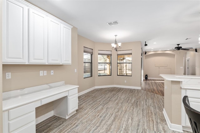 interior space with hanging light fixtures, ceiling fan with notable chandelier, white cabinets, and light wood-type flooring