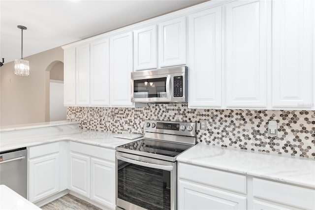 kitchen with white cabinetry, decorative light fixtures, stainless steel appliances, light stone countertops, and backsplash