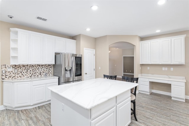 kitchen featuring white cabinetry, tasteful backsplash, stainless steel fridge with ice dispenser, and a kitchen island