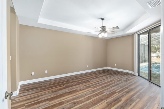 spare room featuring dark wood-type flooring, ceiling fan, and a raised ceiling