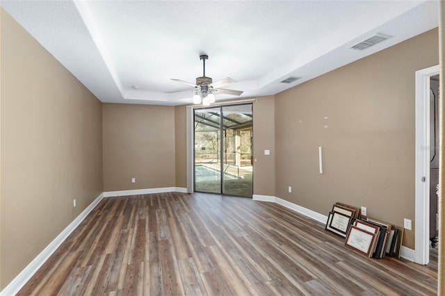 spare room featuring hardwood / wood-style flooring, ceiling fan, and a tray ceiling