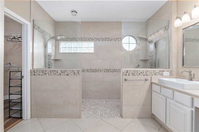 bathroom with a tile shower, vanity, and tile patterned flooring