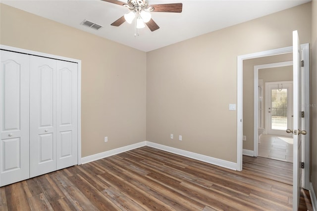 unfurnished bedroom with dark hardwood / wood-style floors, a closet, and ceiling fan