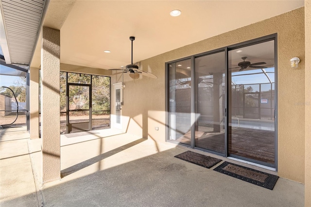 view of patio with ceiling fan and glass enclosure