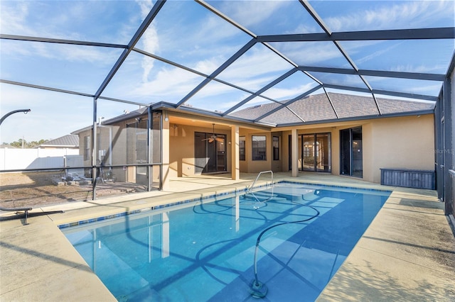 view of swimming pool featuring a patio, ceiling fan, and glass enclosure