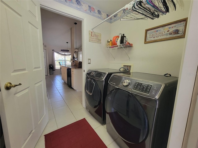 clothes washing area with light tile patterned floors and washer and clothes dryer