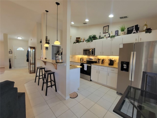 kitchen with appliances with stainless steel finishes, pendant lighting, white cabinets, a kitchen bar, and light tile patterned floors