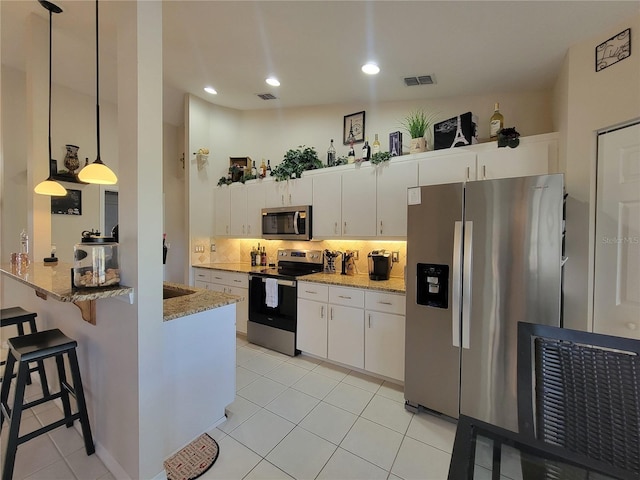 kitchen featuring stainless steel appliances, white cabinetry, kitchen peninsula, and decorative light fixtures