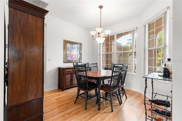 dining space with light hardwood / wood-style floors and a notable chandelier