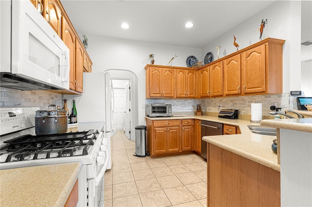 kitchen with light tile patterned flooring, white appliances, sink, and backsplash