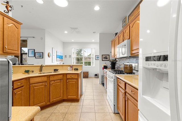 kitchen with light tile patterned flooring, sink, tasteful backsplash, kitchen peninsula, and white appliances