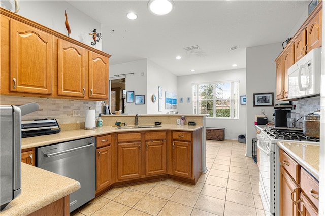 kitchen with tasteful backsplash, sink, white appliances, and kitchen peninsula