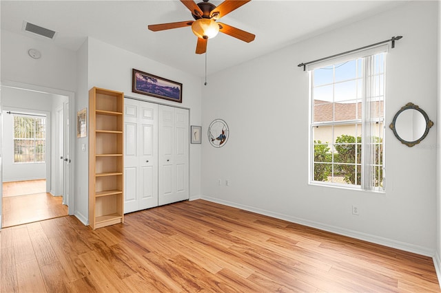 unfurnished bedroom featuring ceiling fan, a closet, and light wood-type flooring