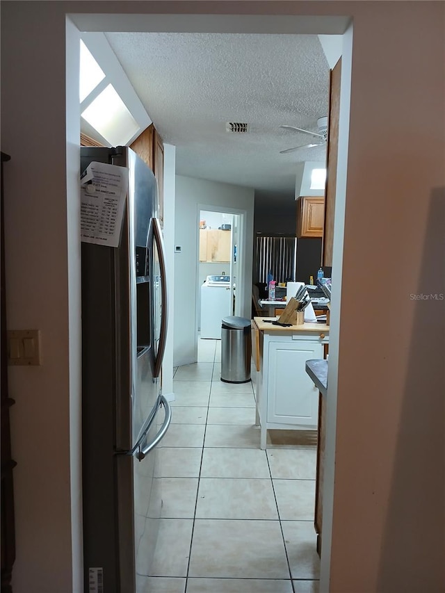 kitchen featuring light tile patterned flooring, separate washer and dryer, ceiling fan, stainless steel fridge with ice dispenser, and a textured ceiling