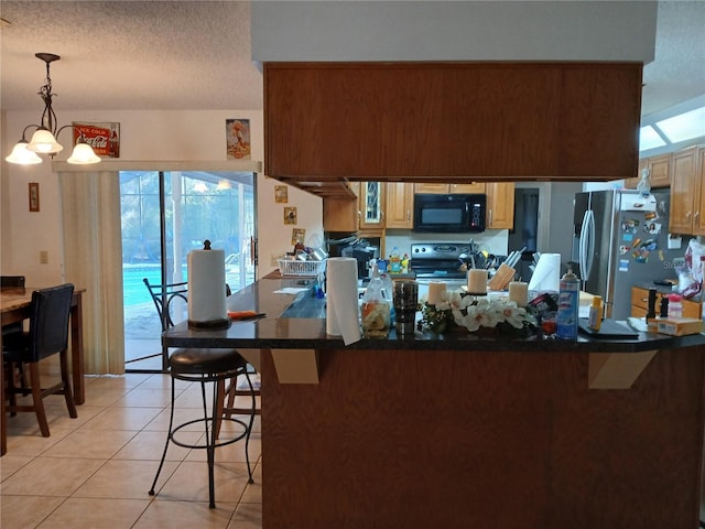 kitchen featuring a kitchen bar, hanging light fixtures, stainless steel refrigerator, kitchen peninsula, and range with electric cooktop