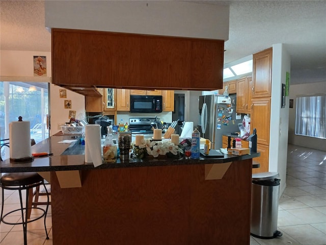 kitchen with light tile patterned flooring, stainless steel appliances, a kitchen breakfast bar, and kitchen peninsula