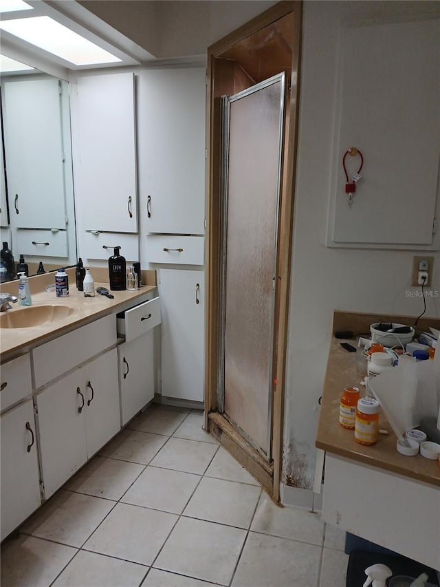 bathroom featuring an enclosed shower, vanity, a skylight, and tile patterned flooring