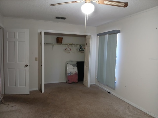 unfurnished bedroom featuring ceiling fan, carpet flooring, a textured ceiling, and a closet