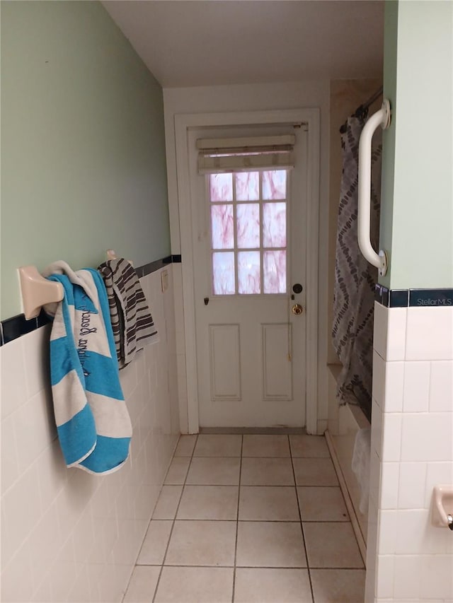 doorway with tile walls and light tile patterned floors