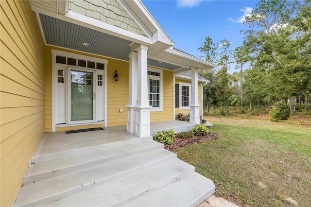 doorway to property featuring covered porch and a lawn