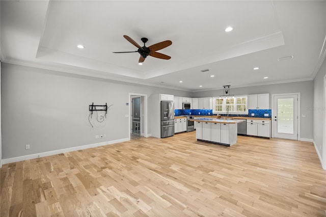 kitchen with a center island, a raised ceiling, and appliances with stainless steel finishes