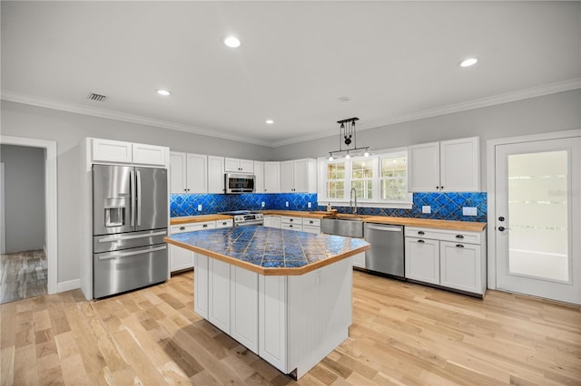 kitchen featuring a kitchen island, appliances with stainless steel finishes, decorative light fixtures, white cabinetry, and sink