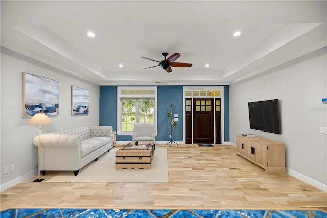 living room featuring ornamental molding, a raised ceiling, and light wood-type flooring